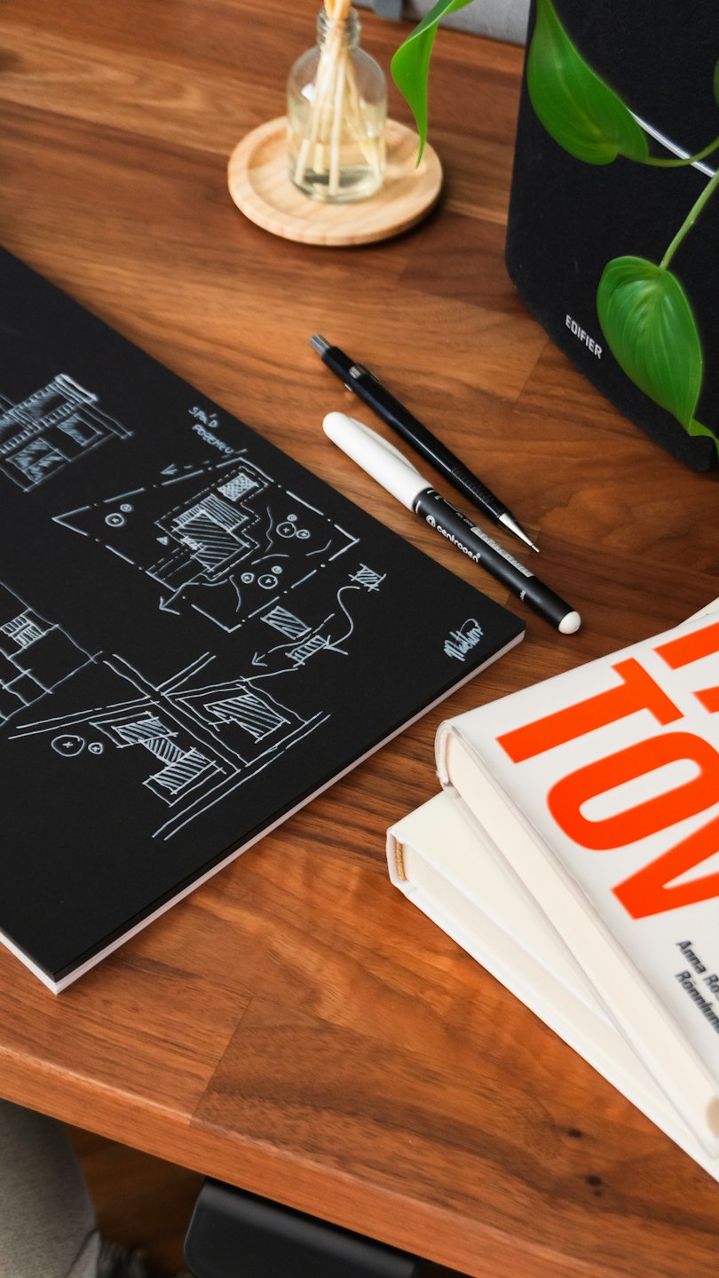 Architectural sketches and office supplies on a polished wooden desk.